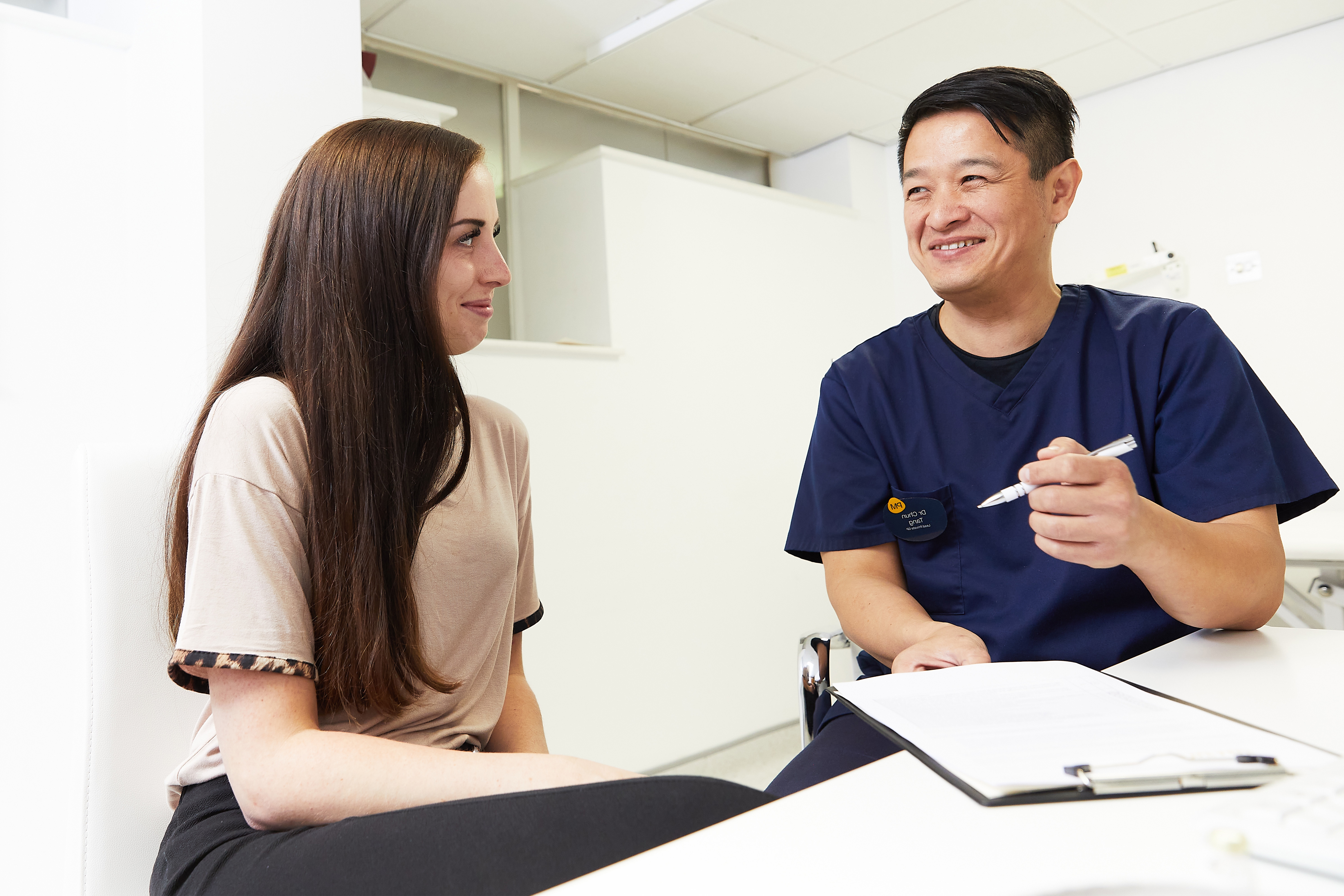 Doctor in blue scrubs sat with female patient Doctor in blue scrubs sat with female patient